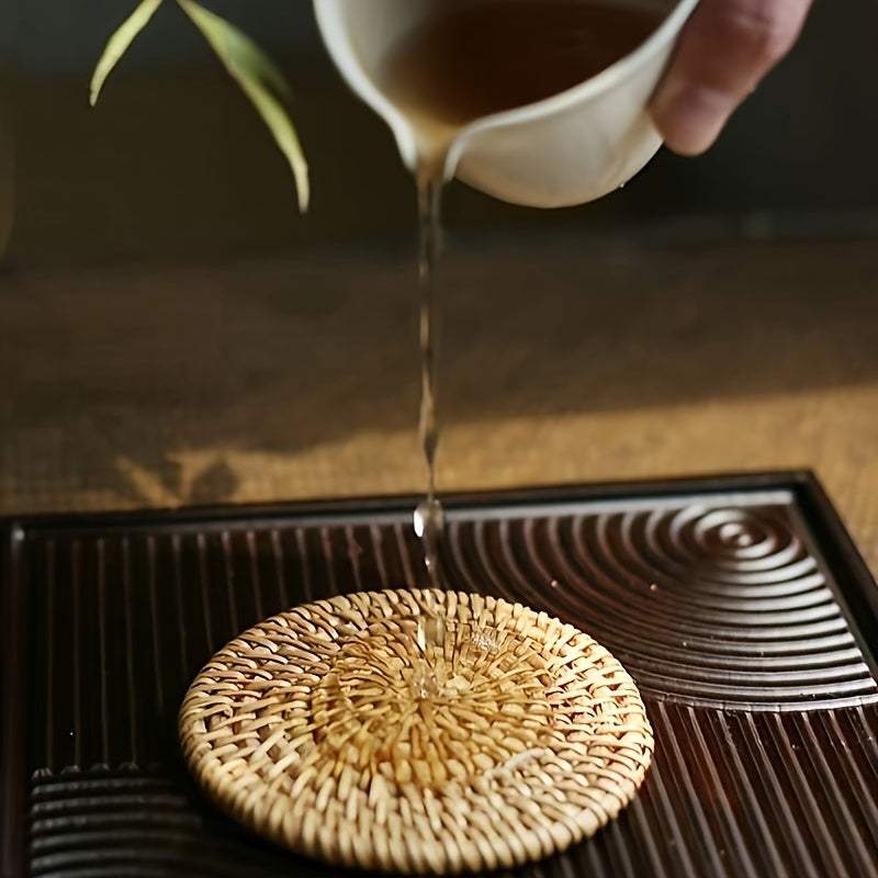 Handmade rattan coaster with tea being poured on a dark wooden tray