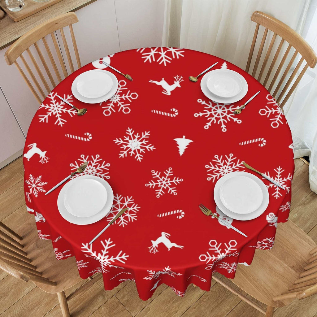 Round red polyester tablecloth with white snowflake, reindeer, and candy cane Christmas pattern on wooden dining table