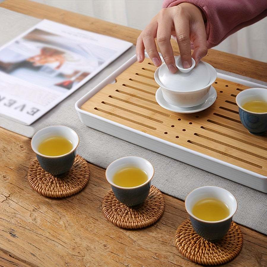Handmade rattan coasters under ceramic tea cups on wooden table with tea set and tray