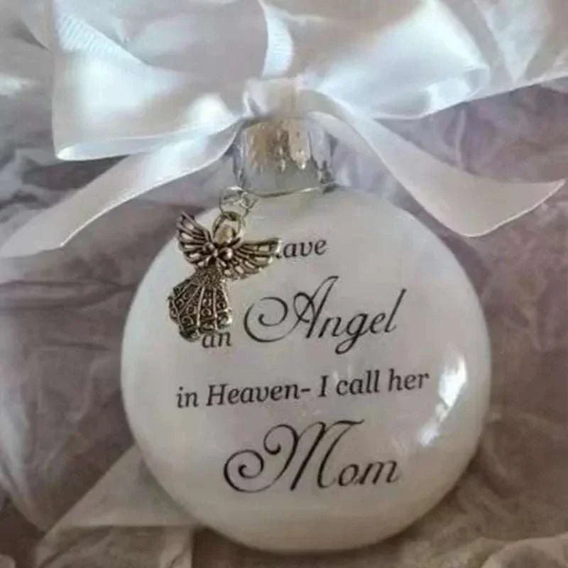 White Christmas memory ball ornament with angel charm and "I have an Angel in Heaven - I call her Mom" inscription hanging with white ribbon