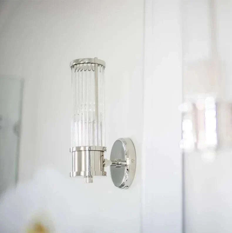 Modern luxury wall lamp with clear glass shade and chrome iron base mounted on white wall