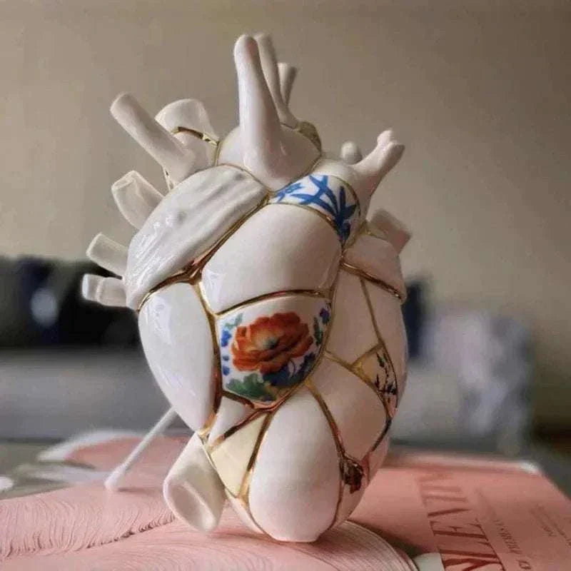 Ceramic vase shaped like an anatomical heart with painted floral and blue designs for home decor