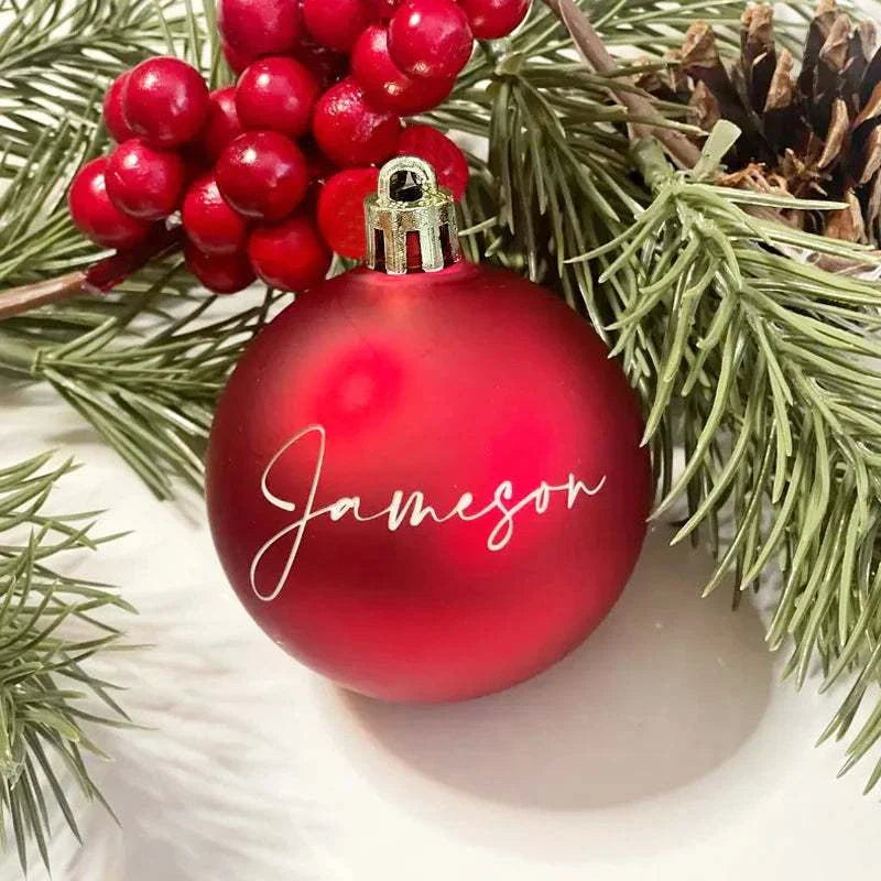 Red personalized Christmas ball ornament with the name Jameson surrounded by pine branches and red berries