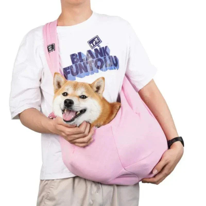 Person carrying a dog in a pink crossbody breathable dog sling bag