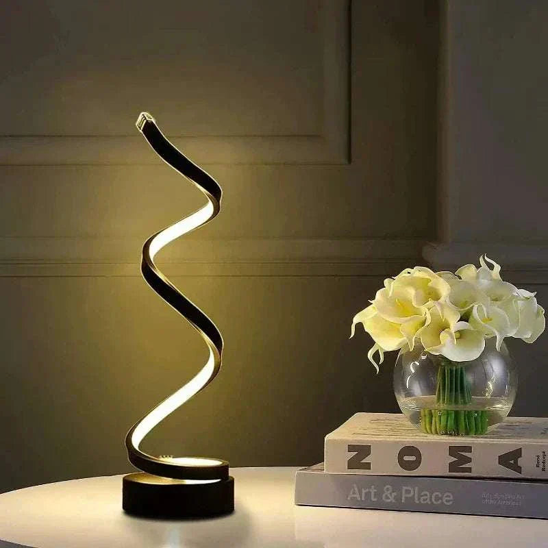 Modern spiral dimmable LED nightstand lamp on table with books and flowers