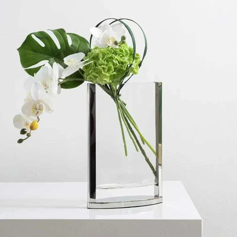 Modern glass vase with green hydrangea, white orchids, and tropical leaf in minimalist home decor style