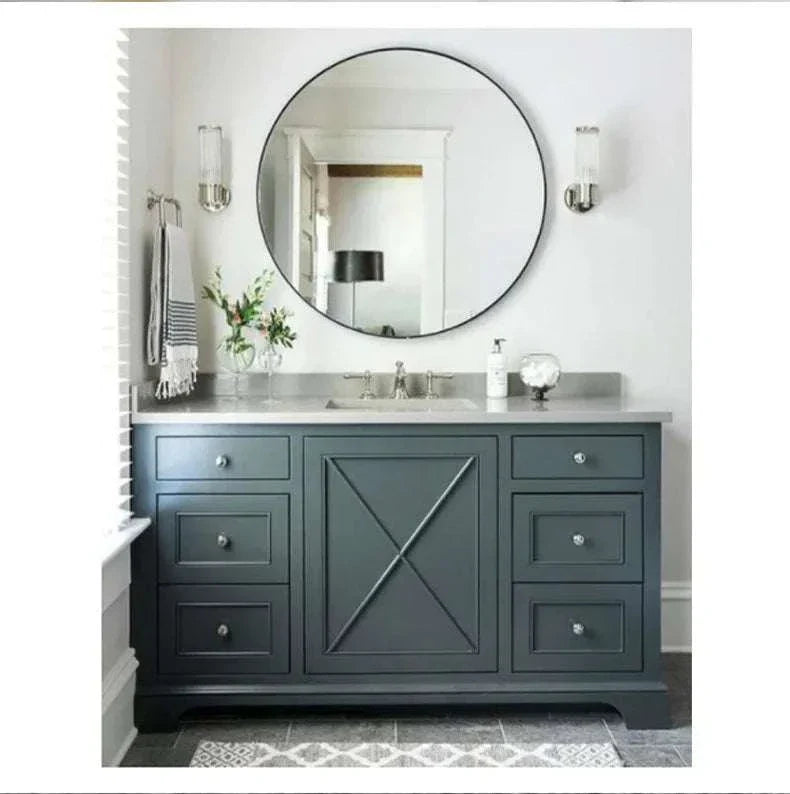 Modern luxury wall lamp with clear glass shade mounted beside bathroom mirror above blue vanity cabinet