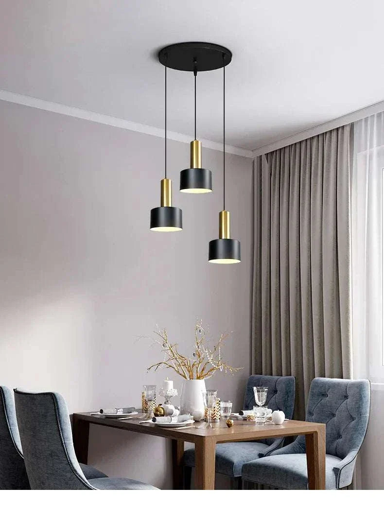 Nordic simple three-chandelier lamp with black and gold metal frame hanging over dining table in modern living room