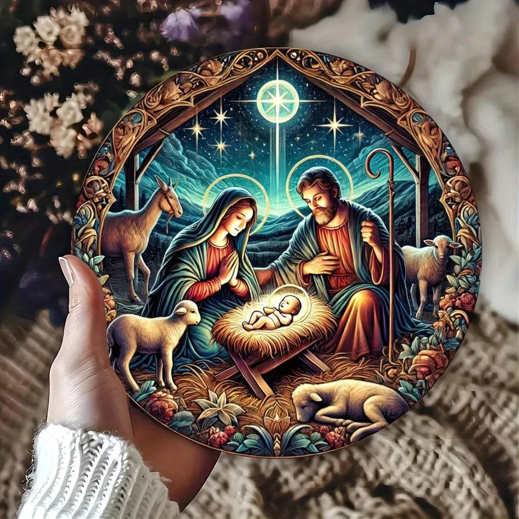 Hand holding round nativity scene aluminum plaque featuring Mary, Joseph, baby Jesus, and animals with starry night background and ornate border.