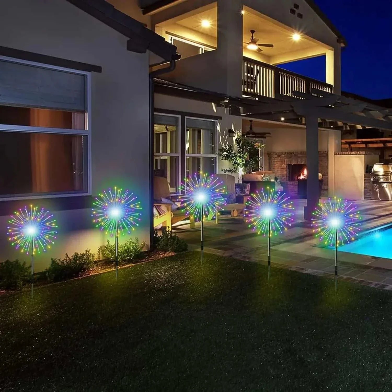 Colorful solar firework string lights glowing in garden at night near modern house and pool