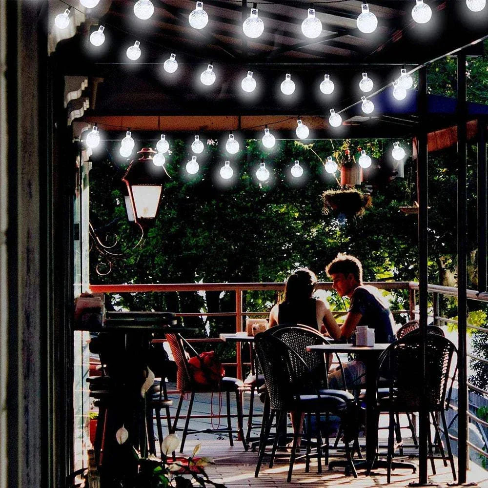 Solar bubble ball string lights illuminating outdoor patio dining area at night