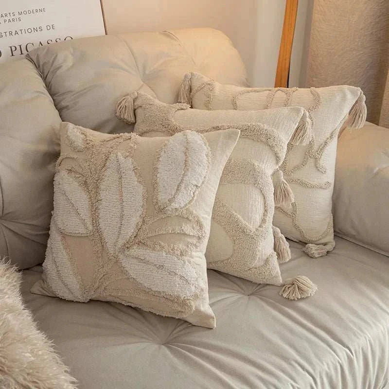 Set of three jacquard embroidery square cushion covers with tassels in neutral beige tones on sofa