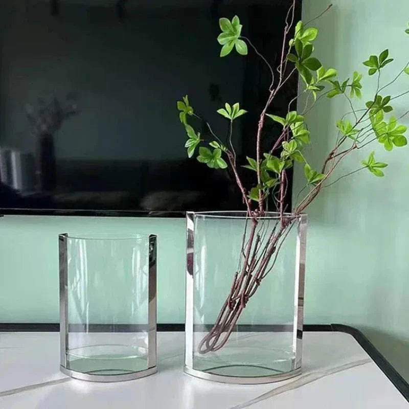 Modern glass vases with metal frames in minimalist Nordic design on table with green branches