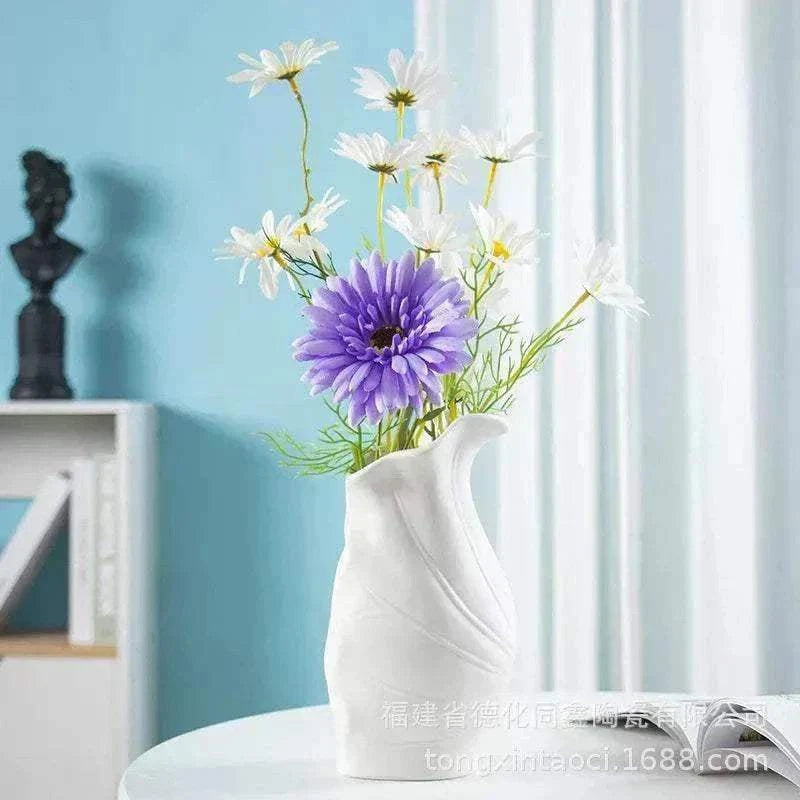 Modern ceramic vase with minimalist French Nordic design holding purple and white flowers on white table