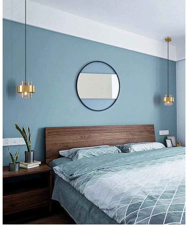 Modern bedroom art decor featuring gold hanging LED pendant lights over a wood bed frame with blue accent wall and round mirror
