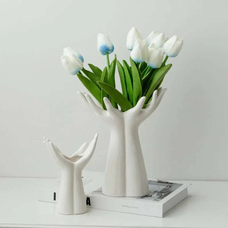 Modern ceramic vase shaped like hands holding flowers with white tulips arrangement
