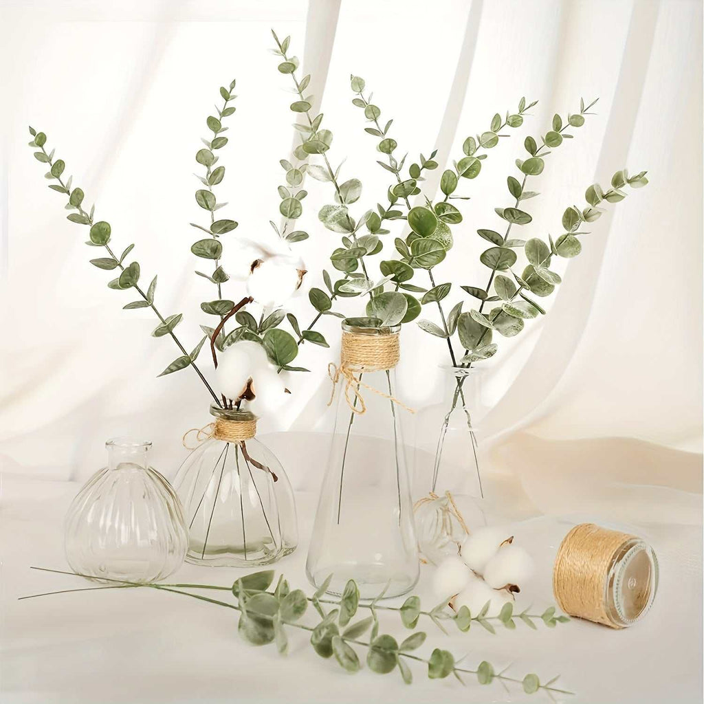 Artificial eucalyptus stems with realistic green leaves in glass vases for wedding and home decor