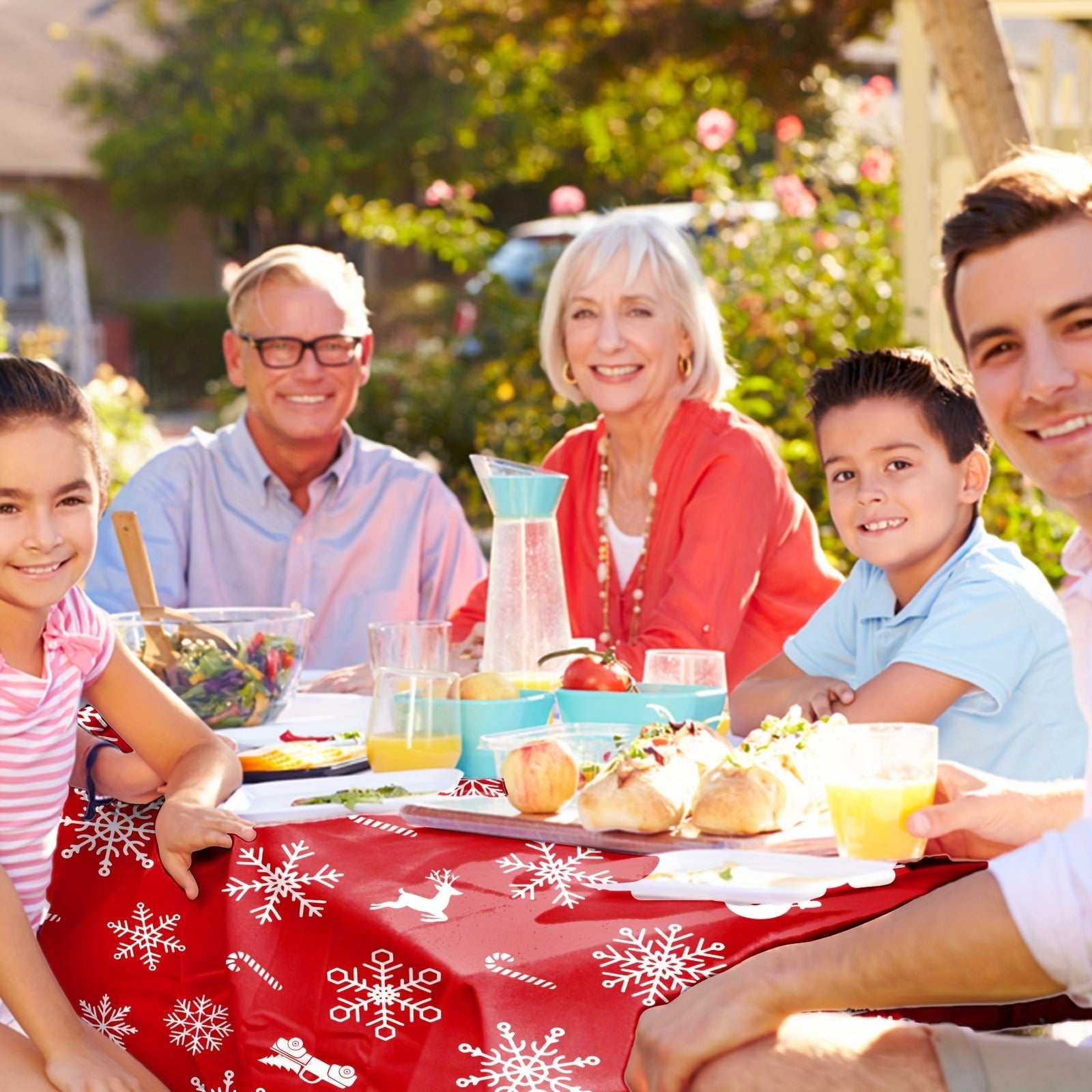 Red polyester Christmas tablecloth with bell and snowflake pattern on outdoor family gathering table